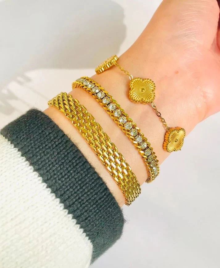 Gold bracelets on a wrist with a neutral background
