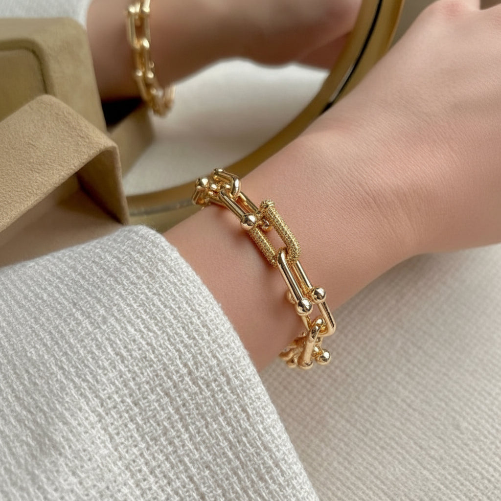 Gold bracelet on a wrist with a neutral background