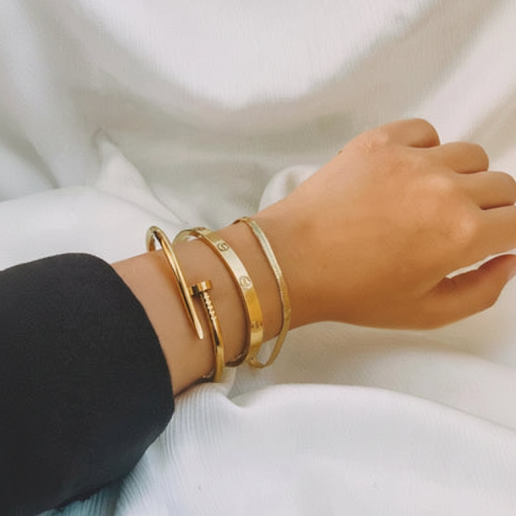 Gold bracelets on a wrist against a white background