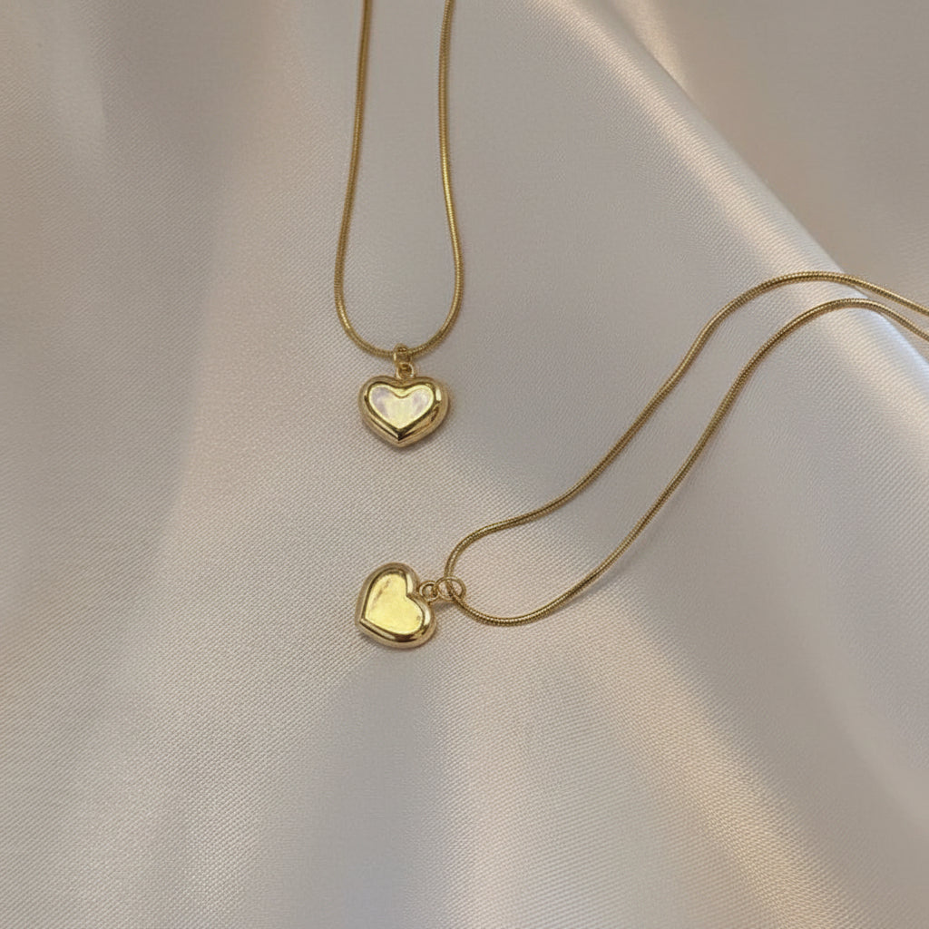 Gold heart-shaped necklace on a beige fabric background
