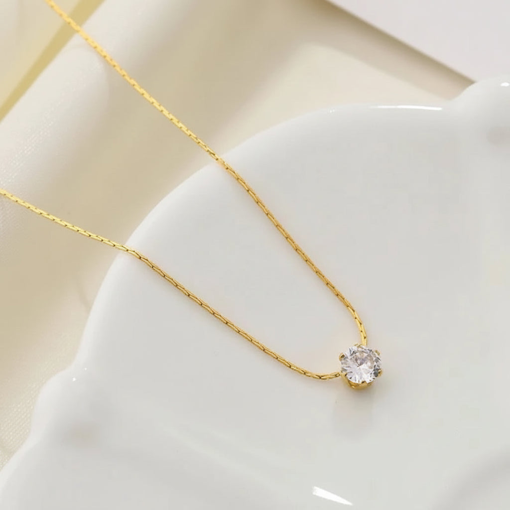 Gold necklace with a heart-shaped pendant on a white surface