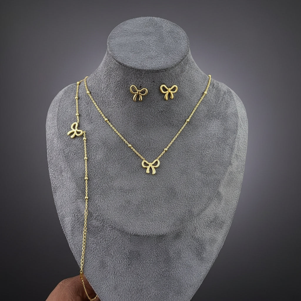 Gold bow-shaped necklace and earrings on a gray mannequin bust.