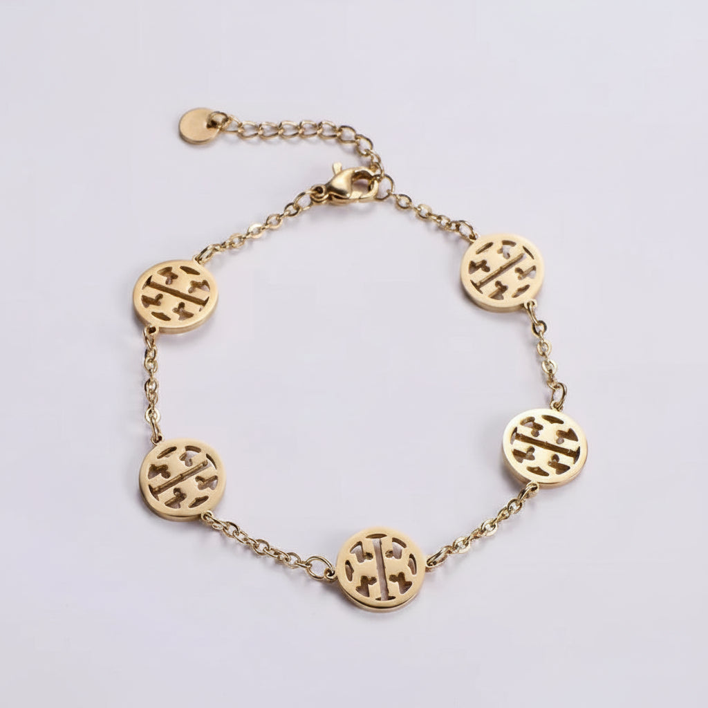A gold-toned chain bracelet featuring five oval cutout charms with a central cross motif, displayed on a light gray background.