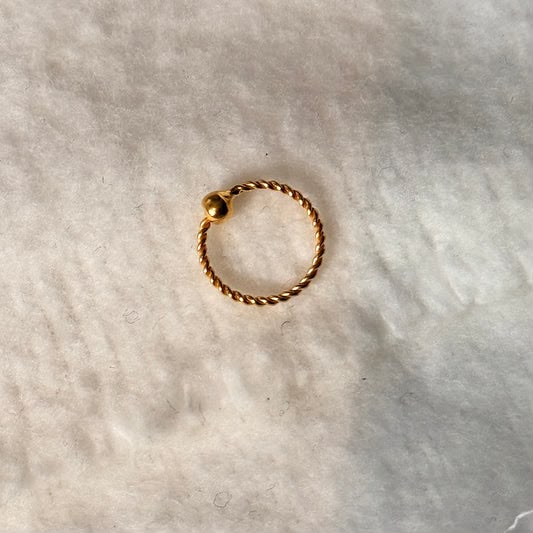 Gold ring with a textured band on a light gray background