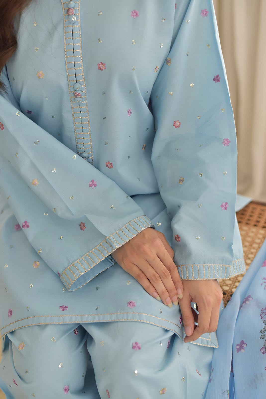 Light blue traditional outfit with floral patterns on a neutral background