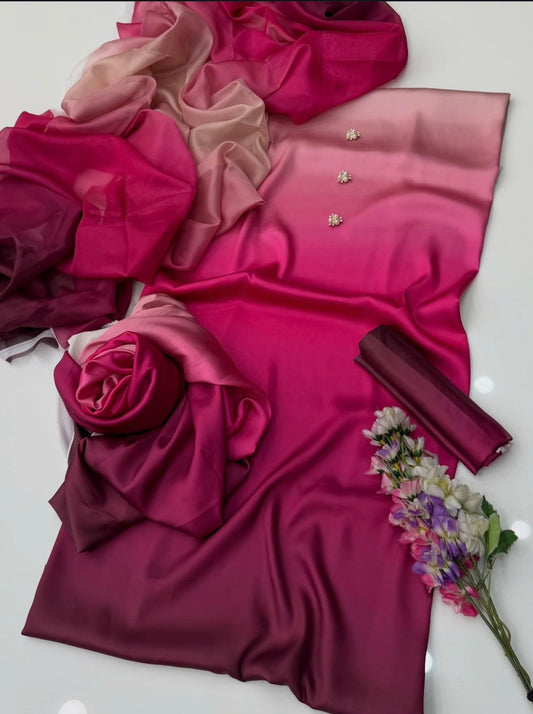A draped fabric set in shades of magenta, deep burgundy, and soft blush pink, styled with a matching sheer scarf, a rolled fabric piece, and a small floral accent on a light background.