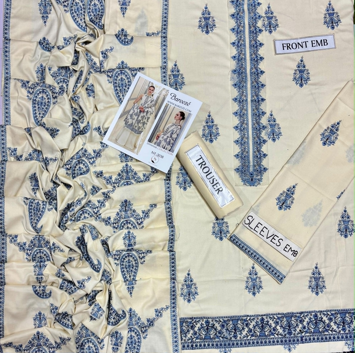 Cream-colored printed cotton fabric set with blue paisley and floral motifs, including a dupatta, trouser, and sleeves, laid out on a white background with product labels.