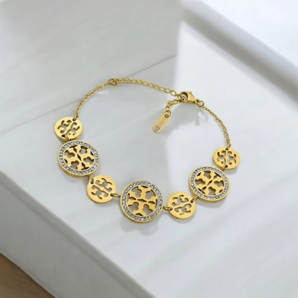 Gold bracelet with circular designs on a white surface