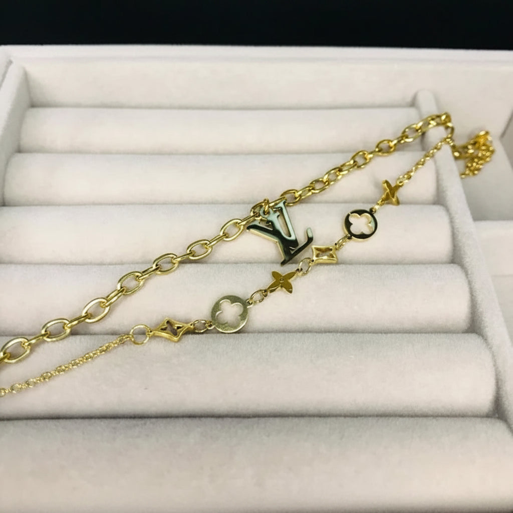 A gold-tone chain bracelet with Louis Vuitton monogram and star motifs, displayed on a white velvet jewelry organizer.