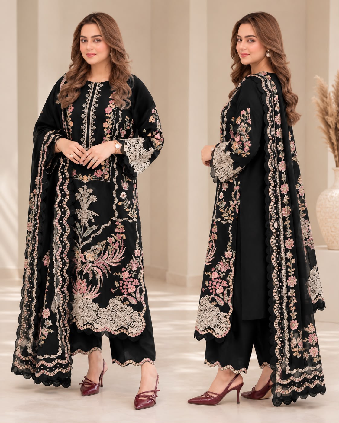 Two women modeling a black traditional embroidered outfit with floral pink and beige embroidery, shown from the front and back in a softly lit indoor studio setting.