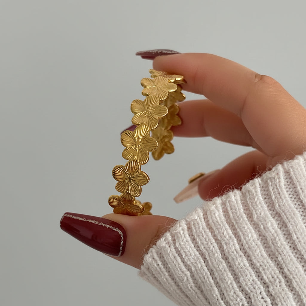 Gold bracelet held by a hand with a blurred background