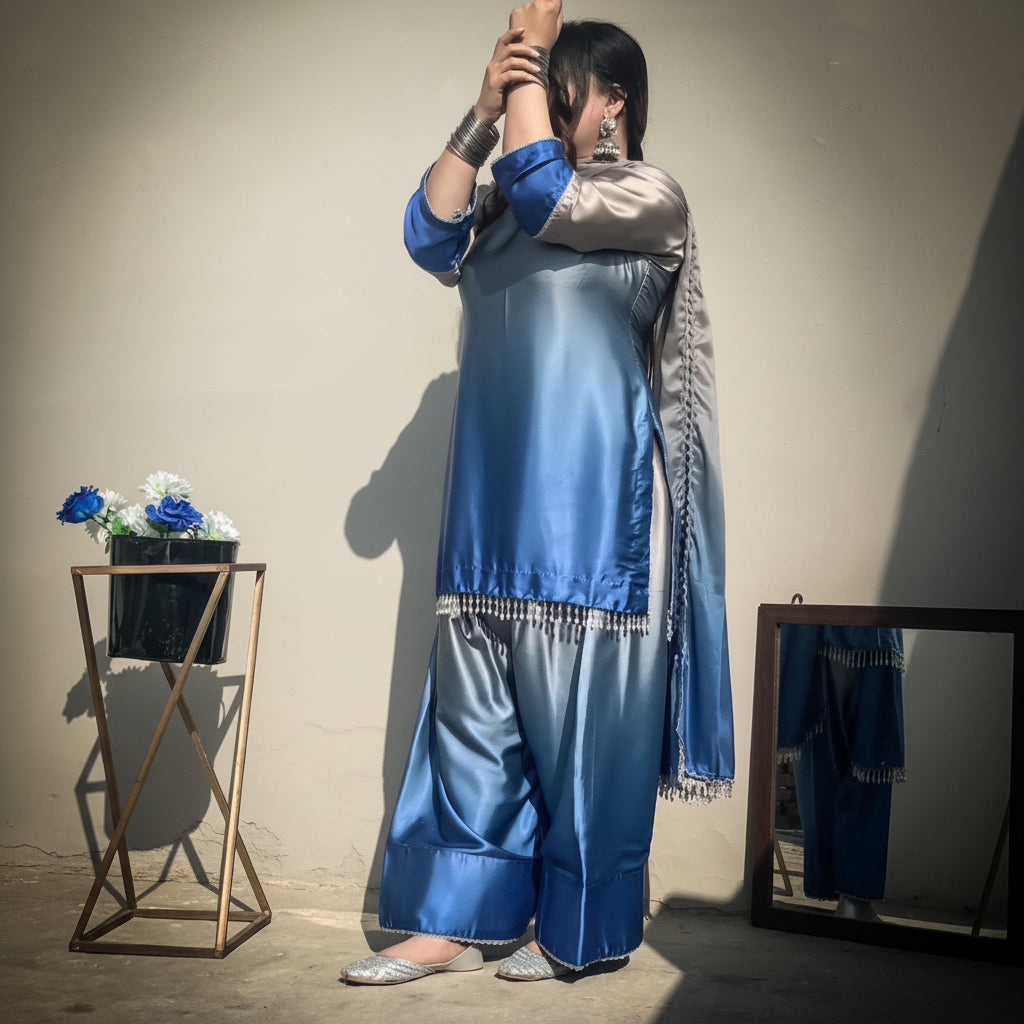 Person wearing a blue and gray traditional outfit with a beige wall background