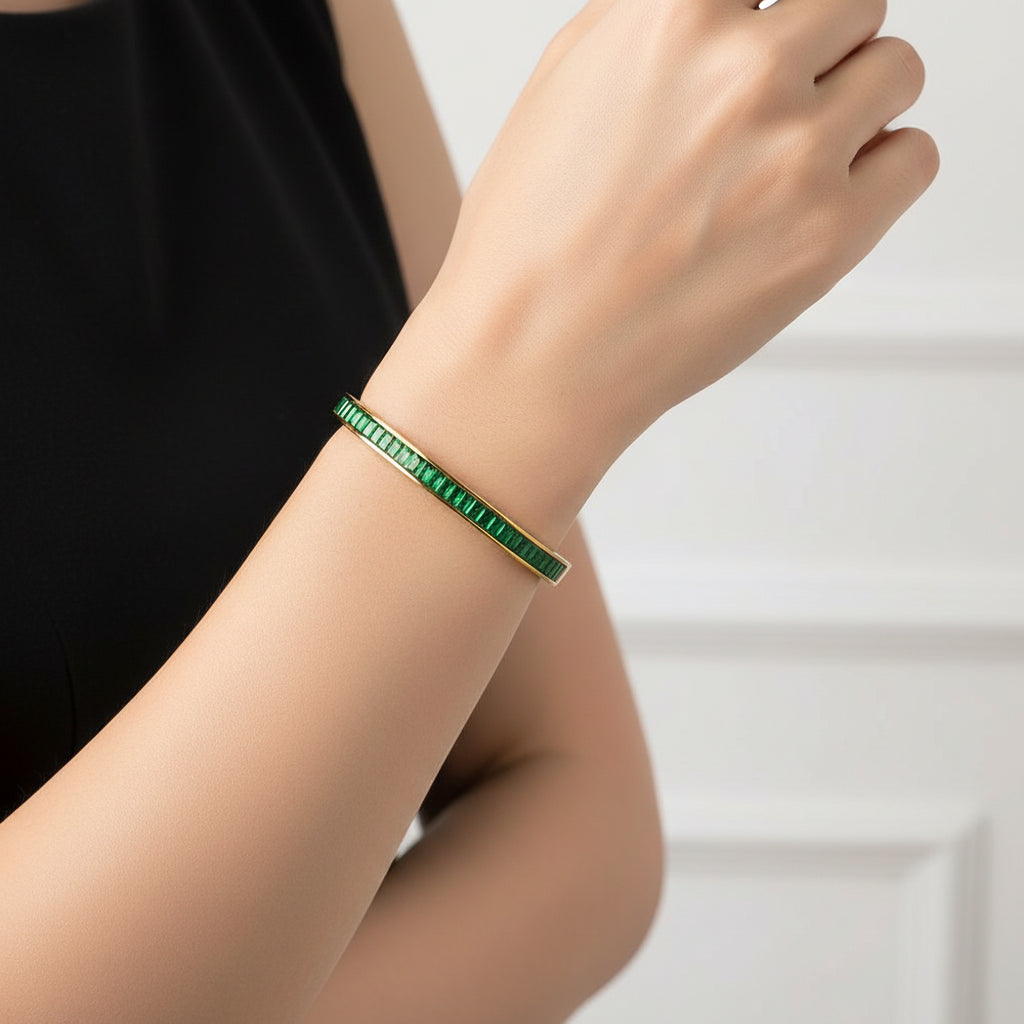 Gold bracelet with green gemstones on a white background