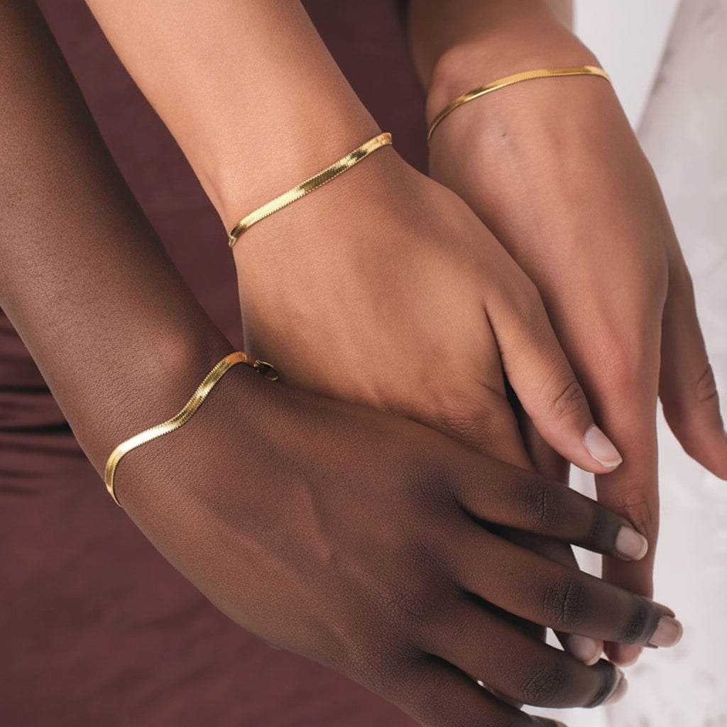 Close-up of hands wearing gold bracelets on a neutral background