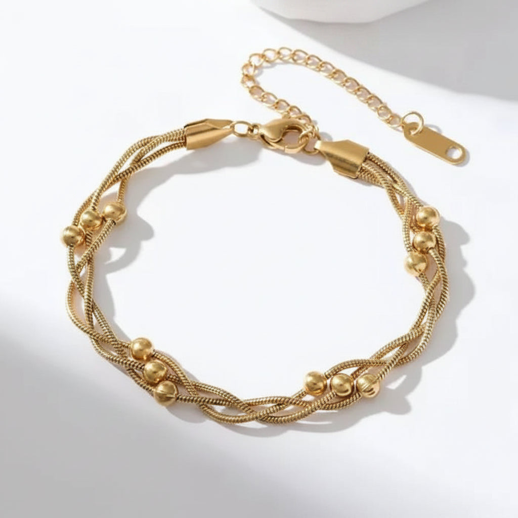 A gold-toned multi-strand chain bracelet with small bead accents, displayed on a clean white background with soft shadows.