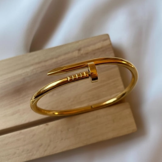 Gold bracelet on a wooden block with a soft background