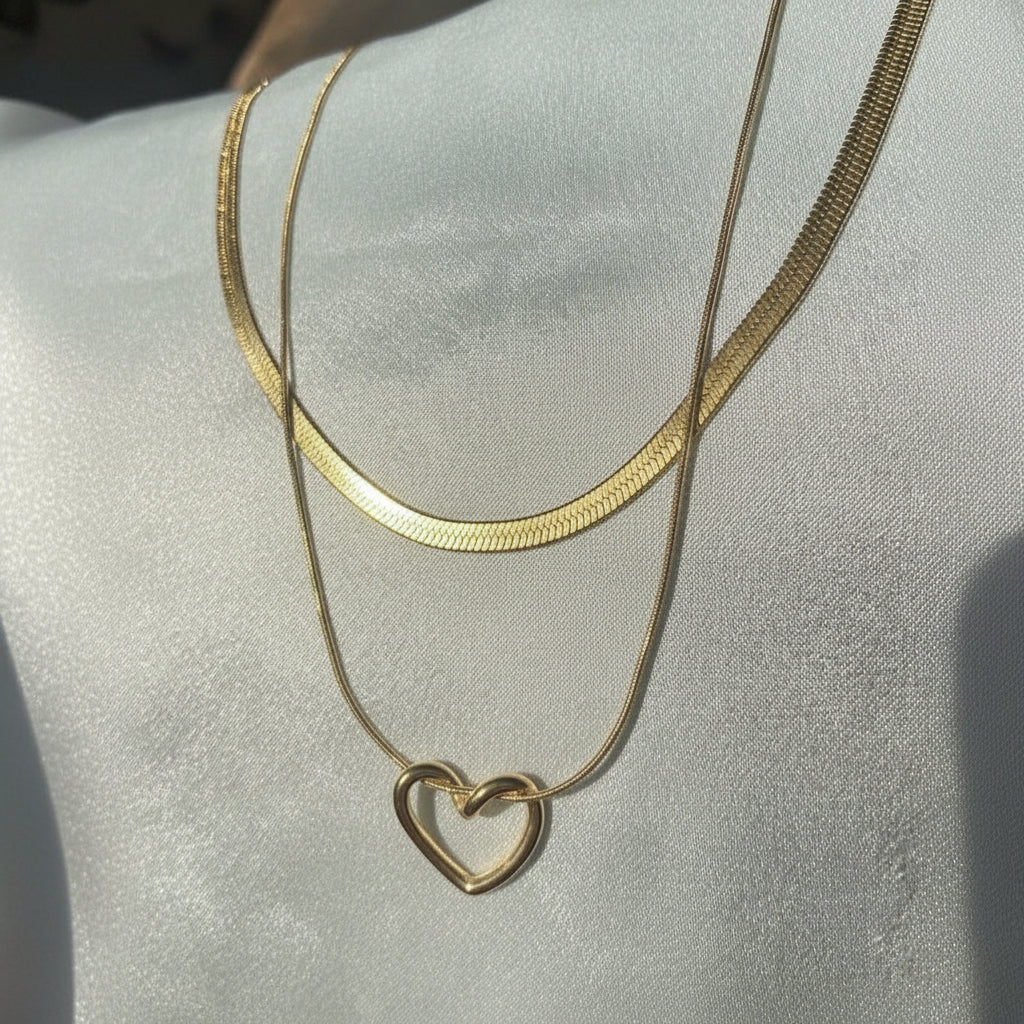 Gold necklace with a heart pendant on a light gray background