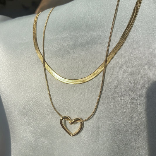 Gold necklace with a heart pendant on a light gray background