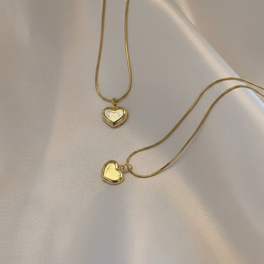 Gold heart-shaped necklace on a beige fabric background