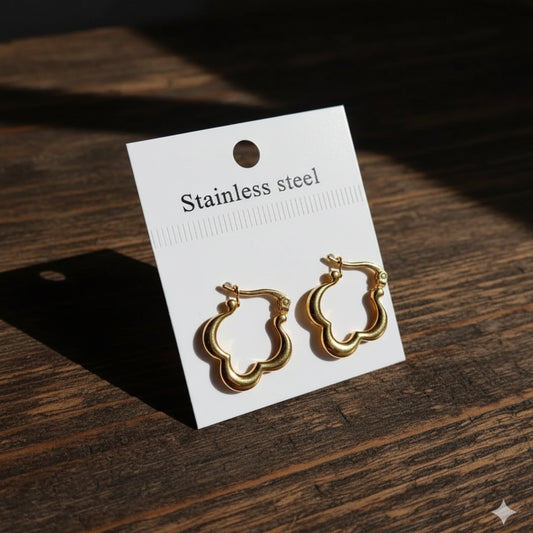 Gold hoop earrings on a white card with 'Stainless steel' text, placed on a light surface.