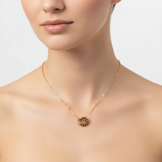A gold chain necklace with a pendant featuring two interlocking rings, one with Roman numerals and the other set with small clear stones, displayed on a white surface.