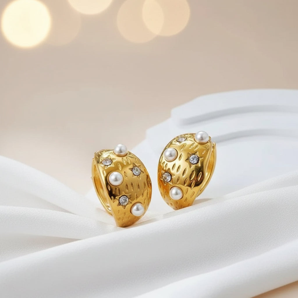 Gold earrings with pearls and gemstones on a white surface