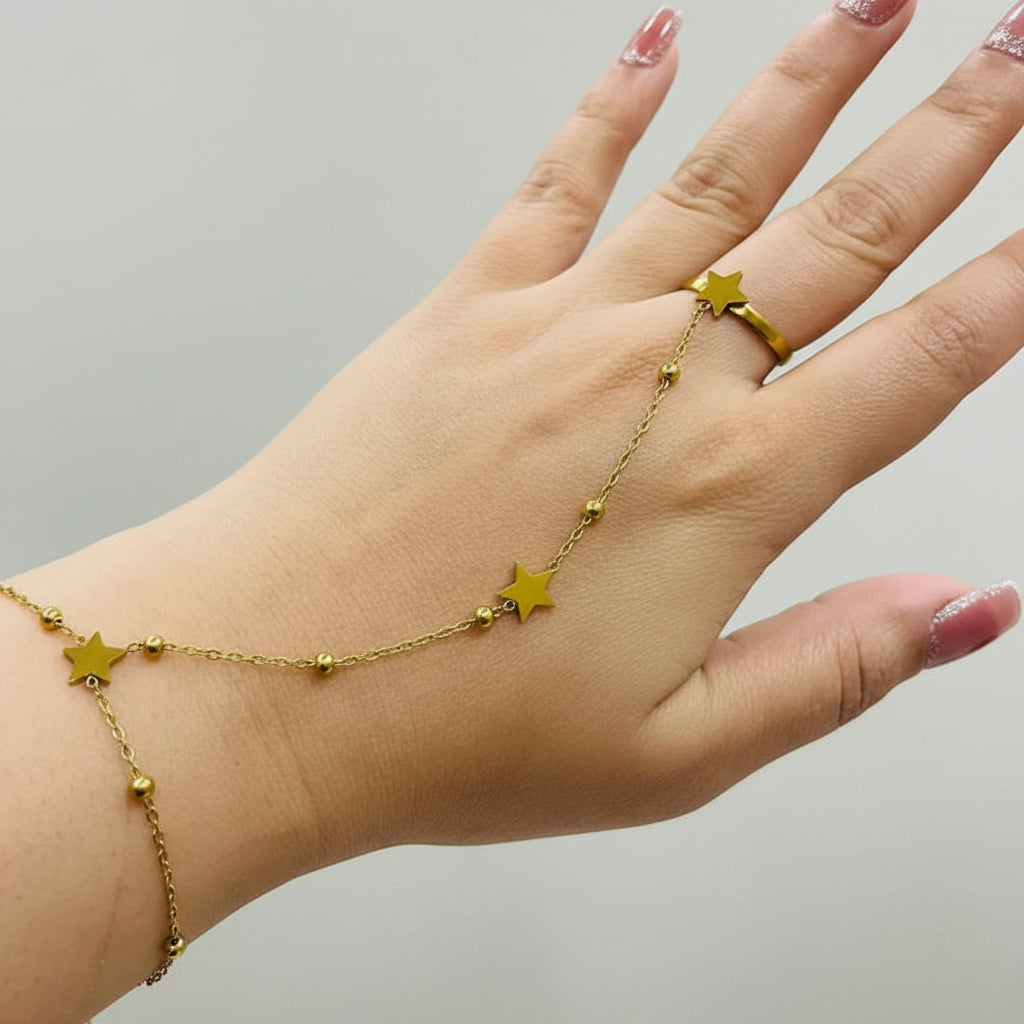 Hand wearing a gold bracelet and ring with star designs.