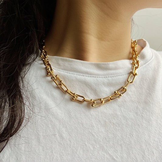 Gold chain necklace worn by a person on a white shirt