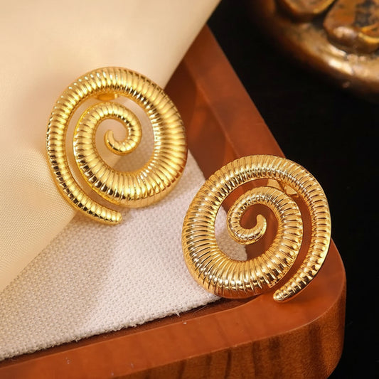 Pair of gold spiral earrings on a wooden surface