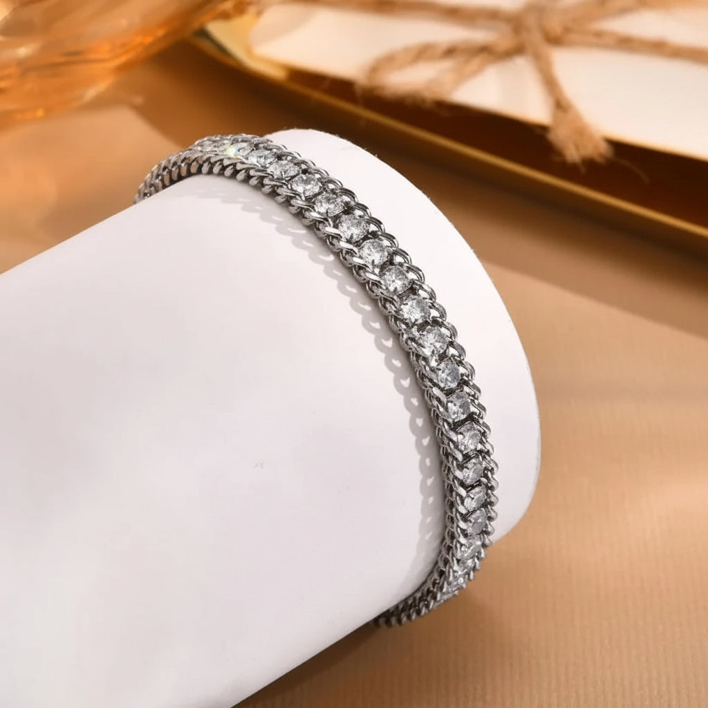 Silver bracelet with clear stones on a white cushion against a beige background