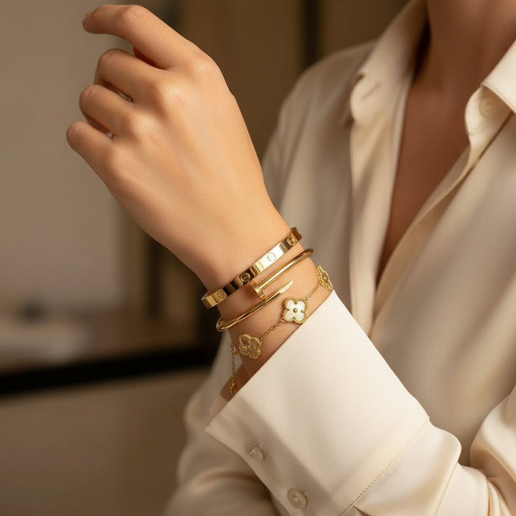 Gold bracelets with clover designs on a white fabric background