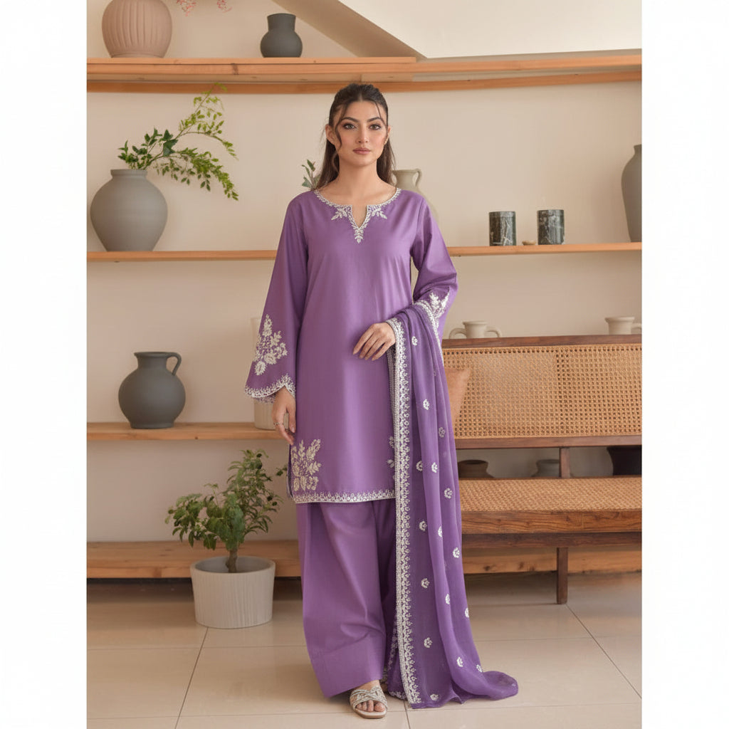 Woman wearing a purple traditional outfit with white embroidery in a home setting.