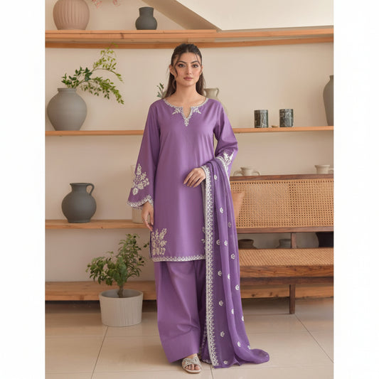 Woman wearing a purple traditional outfit with white embroidery in a home setting.