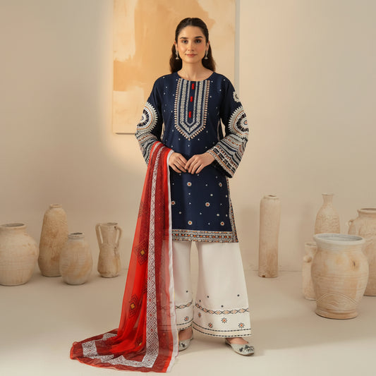 A woman models a traditional South Asian outfit consisting of a navy blue kurta with intricate white and red embroidery, white wide-leg pants, and a red dupatta with white borders, set against a warm beige background with decorative ceramic vases.