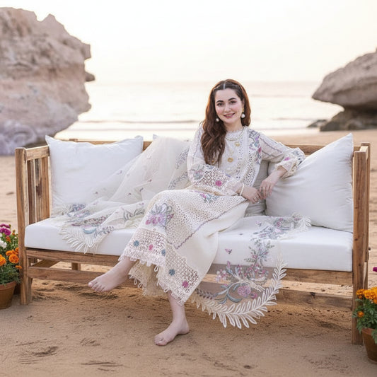 Woman in a floral dress sitting on a wooden bench by the beach.
