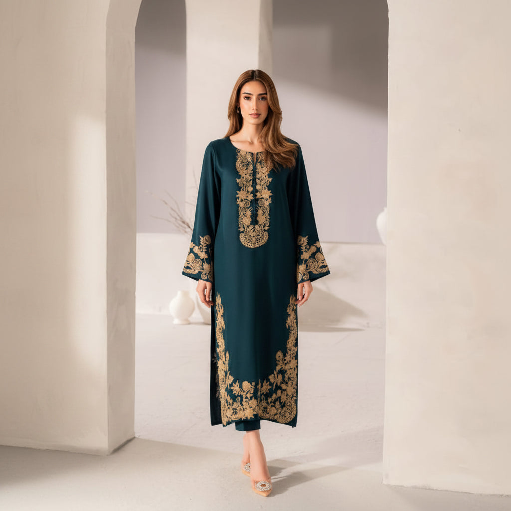 Woman wearing a teal dress with gold embroidery in a minimalistic setting