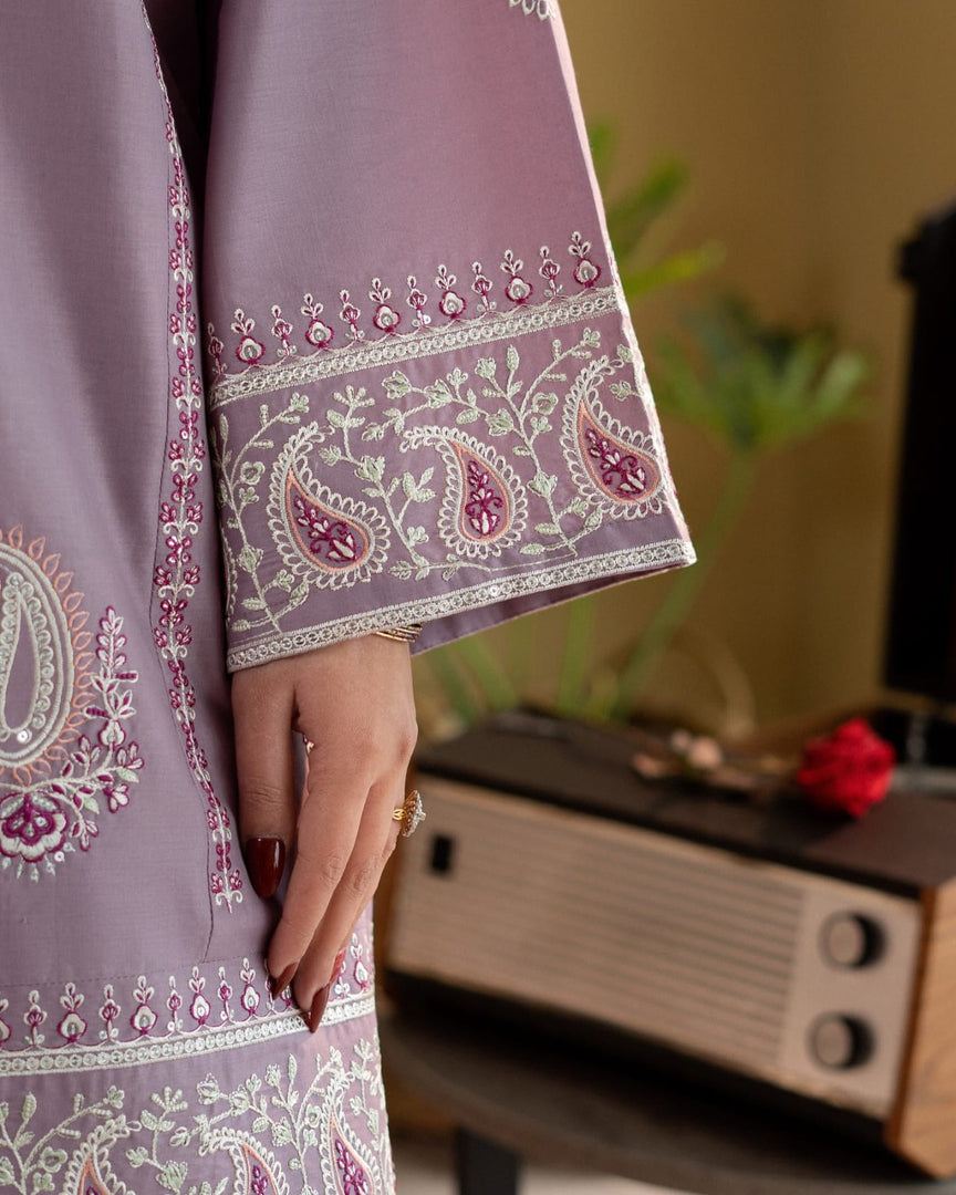 Purple embroidered fabric with a hand holding it, blurred background