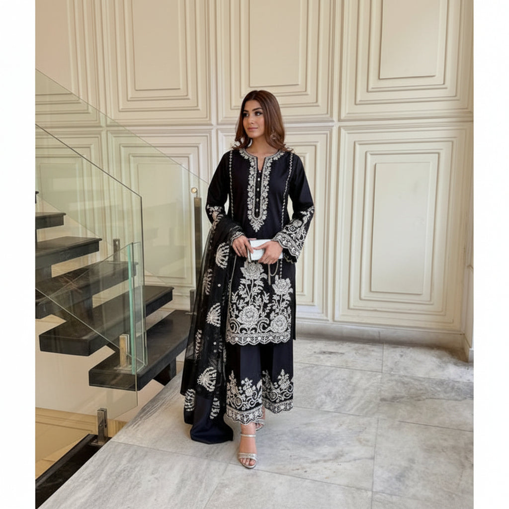 Woman in black outfit with floral details standing in a stylish interior setting