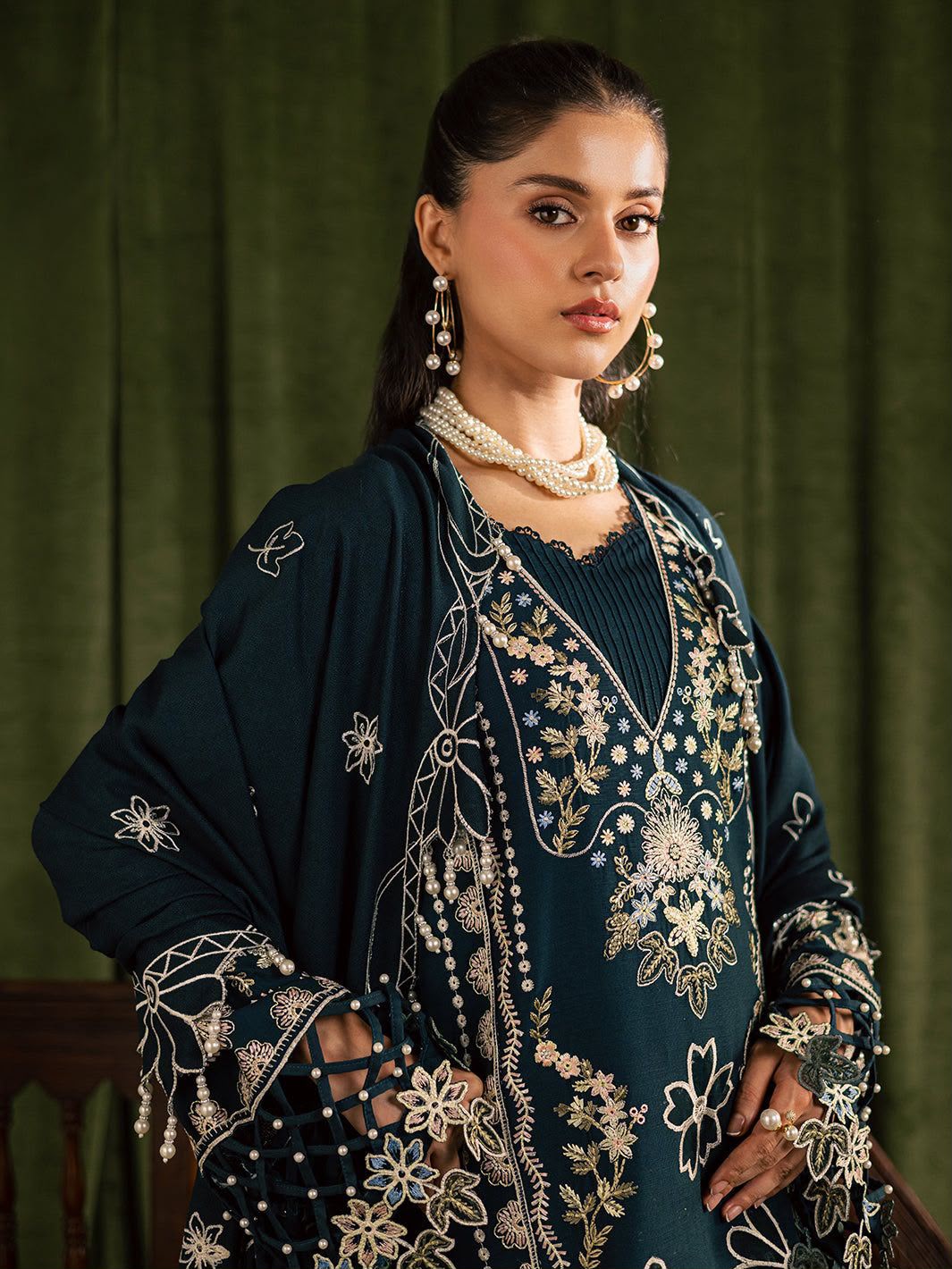 Woman wearing an embroidered traditional outfit against a green curtain background