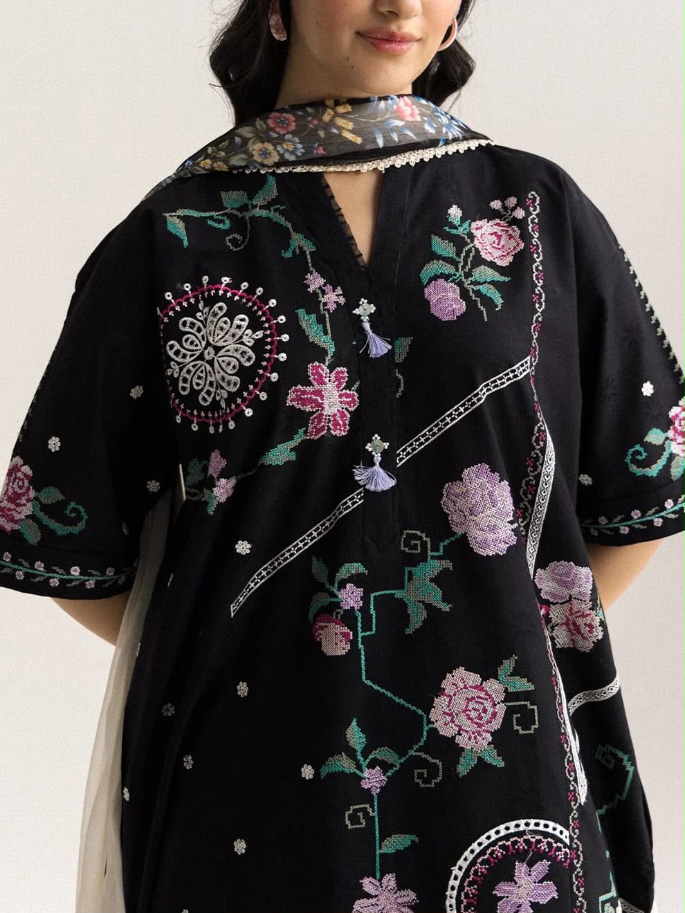 Black embroidered dress with floral patterns on a plain background