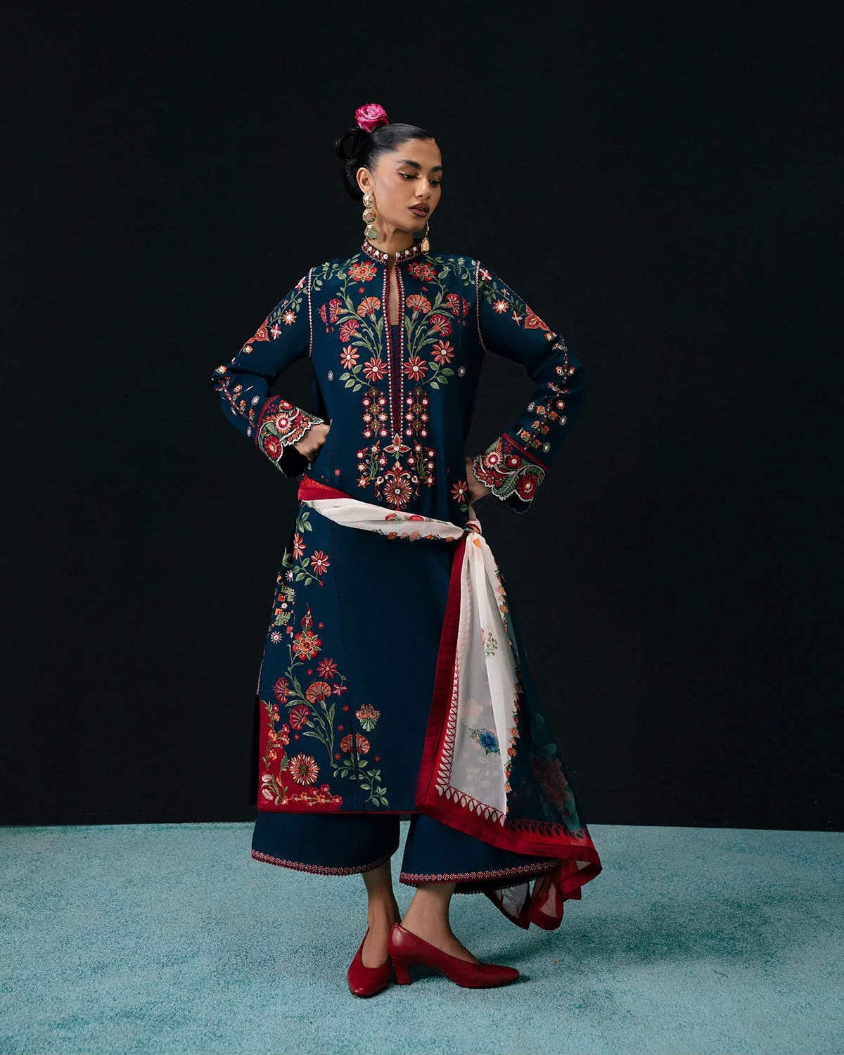 Woman wearing a traditional embroidered outfit with a black background