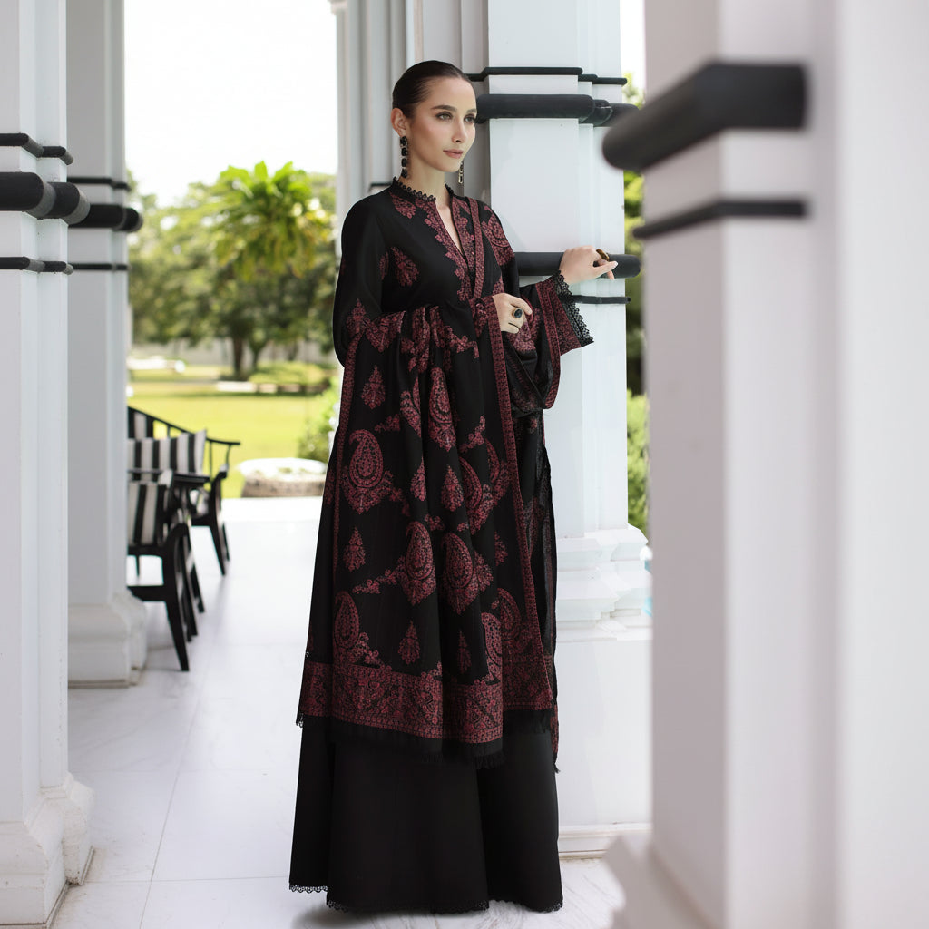 Woman in a black and red patterned dress standing in a doorway.