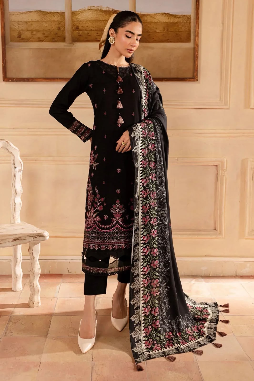 Woman in a black embroidered outfit with a matching dupatta in an elegant room.