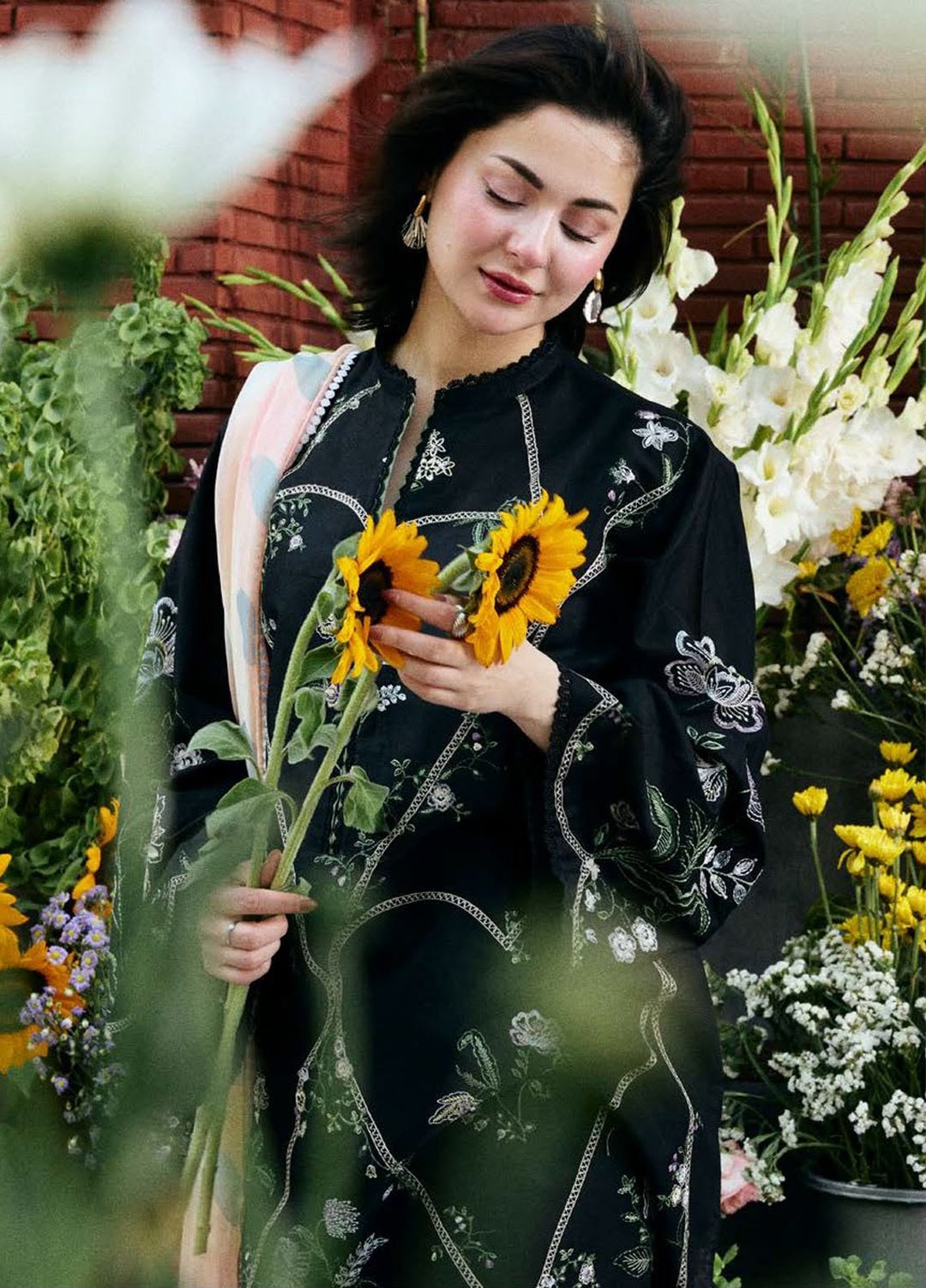 Woman holding sunflowers among flowers and plants