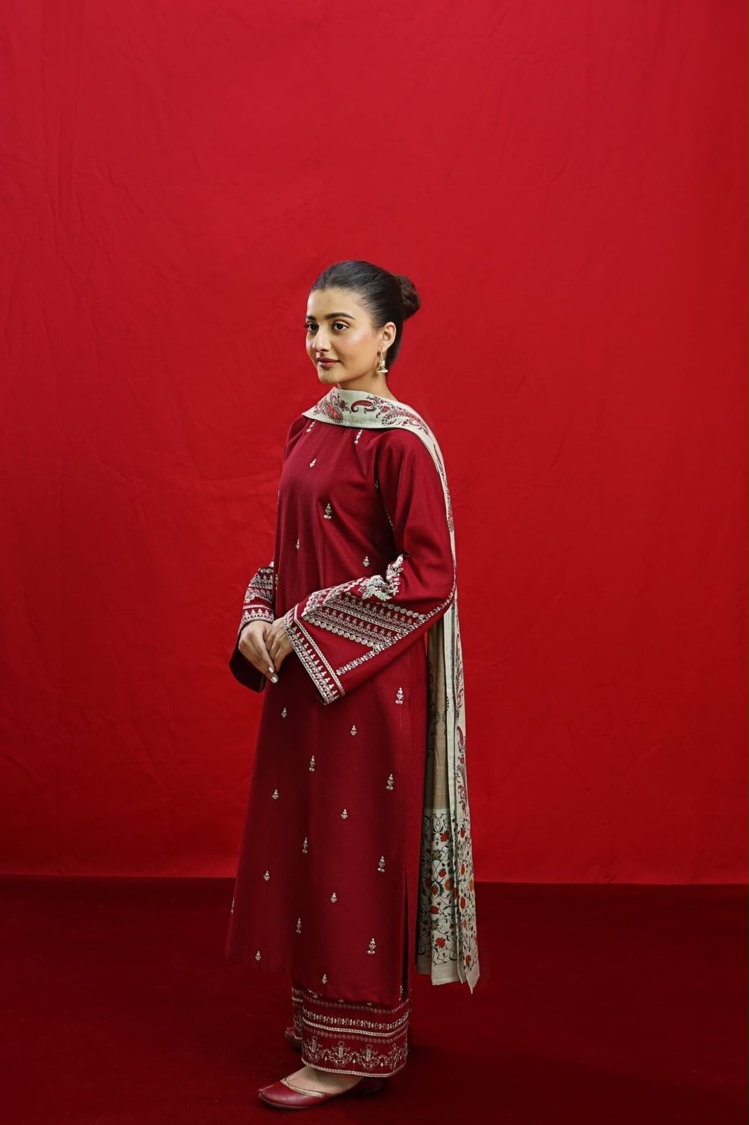 Woman in a red traditional outfit with white patterns against a red background