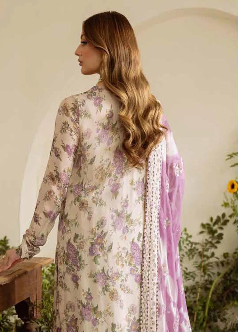 A woman shown from the back wearing a floral long kurta in cream with purple and green floral print, paired with a light purple dupatta, in an indoor setting with plants.