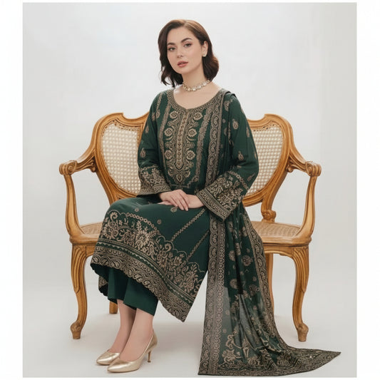 A woman seated on an ornate wooden cane-back bench wearing a dark green traditional outfit with extensive gold embroidery and a matching dupatta, photographed against a plain light background.