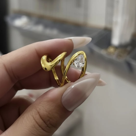 Gold ring with a diamond held between fingers against a blurred background