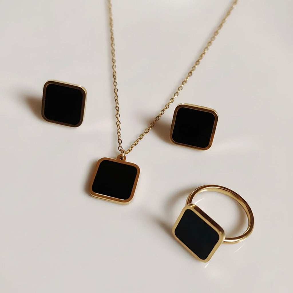 Jewelry set with square black stones and gold accents on a light background