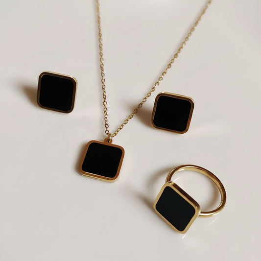 Jewelry set with square black stones and gold accents on a light background